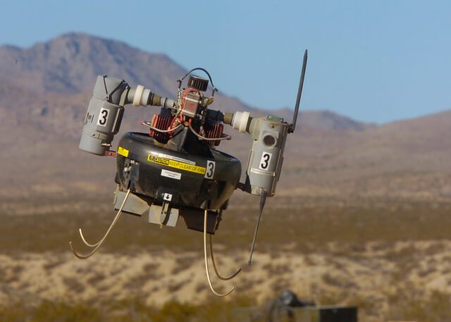 A Micro Air Vehicle flies over a simulated combat area. 3W